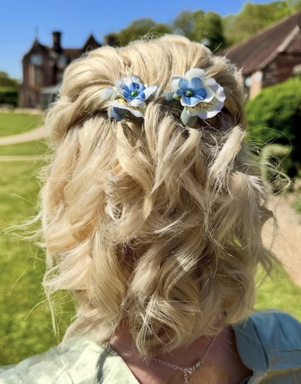 Blonde curled updo with blue and white flower accessories
